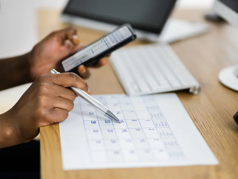 Effective scheduling tools displayed with a person using a paper calendar and mobile app together
